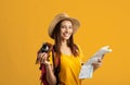 Happy young woman backpacker holding city map and camera