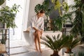 Happy young woman in bathrobe dry brushing her legs with a natural brush while sitting on the side of a bathtub in the Royalty Free Stock Photo