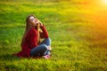 Happy young woman. Beautiful female with long healthy hair enjoying sun light in park sitting on green grass. Spring Royalty Free Stock Photo