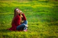 Happy young woman. Beautiful female with long healthy hair enjoying sun light in park sitting on green grass. Spring Royalty Free Stock Photo