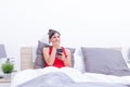 Happy young woman in bed looking surprised with mobile phone in her hand Royalty Free Stock Photo