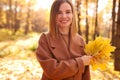 Happy young woman in a beige coast walks outdoors in autumn park, concept autumn. Royalty Free Stock Photo