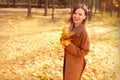 Happy young woman in a beige coast walks outdoors in autumn park, concept autumn. Royalty Free Stock Photo