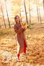 Happy young woman in a beige coast walks outdoors in autumn park, concept autumn. Royalty Free Stock Photo