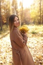 Happy young woman in a beige coast walks outdoors in autumn park, concept autumn. Royalty Free Stock Photo