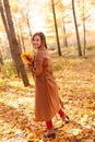 Happy young woman in a beige coast walks outdoors in autumn park, concept autumn. Royalty Free Stock Photo