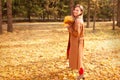 Happy young woman in a beige coast walks outdoors in autumn park, concept autumn. Royalty Free Stock Photo