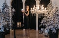 A happy young woman in a black dress holds a Christmas decoration in her hands. Makes a wish for the new year. Festive Royalty Free Stock Photo