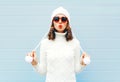 Happy young woman blowing red lips makes air kiss wearing a heart shape sunglasses, knitted hat, sweater over blue Royalty Free Stock Photo