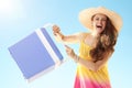 Happy young woman with blue plastic cooler box against blue sky