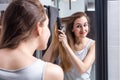 Happy young woman brushing long hair in front of mirror Royalty Free Stock Photo