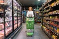 Happy young woman buying food in supermarket, walking with shop cart and looking at shelfs, full length shot. Female Royalty Free Stock Photo