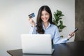 Happy young woman buying things online with copy space, using smartphone, laptop and credit card, enjoying shopping in internet Royalty Free Stock Photo