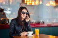 Happy young woman at cafe drinking coffee and talking on the mobile phone Royalty Free Stock Photo