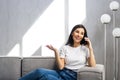 Happy young woman caller talking on the phone at home, cheerful teen girl enjoys pleasant mobile conversation in living room Royalty Free Stock Photo