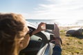 Happy young woman in car with smartphone at sea Royalty Free Stock Photo