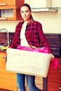 Happy young woman carrying laundry basket in kitchen Royalty Free Stock Photo