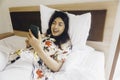 Happy young woman checking on her phone while lying in bed Royalty Free Stock Photo