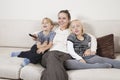 Happy young woman with children on sofa watching TV Royalty Free Stock Photo