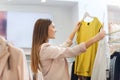 Happy young woman choosing clothes in mall