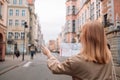 Happy young woman with a city map traveling, exploring new city. Woman holding a paper map on central square in Gdansk Royalty Free Stock Photo