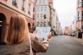 Happy young woman with a city map traveling, exploring new city. Woman holding a paper map on central square in Gdansk Royalty Free Stock Photo