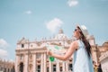 Happy young woman with city map in Vatican city and St. Peter`s Basilica church, Rome, Italy.