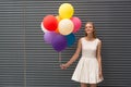 Happy young woman with colorful balloons on a street near the gray - outdoors summer concept Royalty Free Stock Photo