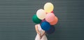 Happy young woman with colorful balloons on a street near the gray - outdoors summer concept Royalty Free Stock Photo