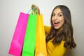 Happy young woman with colorful shop bags full of clothes in her hand on gray background
