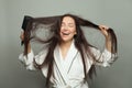 Happy young woman combing her tangled hair and smiling on white background. Morning routine concept Royalty Free Stock Photo