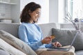 Happy young woman consumer holding credit card and laptop buying online at home. Royalty Free Stock Photo