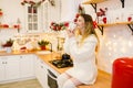 Happy young woman with cup of coffee in red christmas decorated kitchen Royalty Free Stock Photo