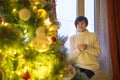 Happy young woman with cup of coffee or tea at home over christmas tree Royalty Free Stock Photo