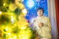 Happy young woman with cup of coffee or tea at home over night sky and moon with snowfall and christmas tree. The Royalty Free Stock Photo