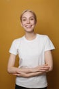 Happy young woman with cute friendly smile on vivid yellow studio background
