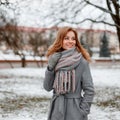 Happy young woman with a cute smile in warm gloves in a winter fashionable coat with a knitted vintage scarf posing Royalty Free Stock Photo