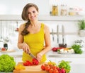 Happy young woman cutting fresh vegetable salad