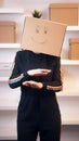 Happy young woman dancing with a cardboard box over her head. Relocation and purchase of real estate Royalty Free Stock Photo