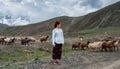 Happy young woman in a denim shirt against herds of sheep