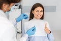 Happy young woman in dentist chair showing thumb up Royalty Free Stock Photo