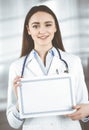 Happy young woman-doctor is holding a certificate in her hands. Professional physician at work in a clinic. Medicine