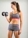 Happy young woman doing dumbbell curl