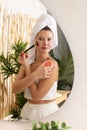 A happy young woman is doing makeup with a blush brush in front of the bathroom mirror. Royalty Free Stock Photo