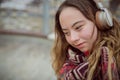 Happy young woman with Down syndrome listening to music in town in winter Royalty Free Stock Photo