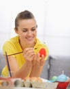 Happy young woman drawing on Easter red egg Royalty Free Stock Photo