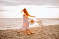 Happy young woman in a dress holding straw hat and walking alone on empty sand beach at sunset sea shore and smiling. Freedoom, Royalty Free Stock Photo