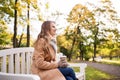 Happy young woman drinking coffee in autumn park Royalty Free Stock Photo