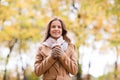 Happy young woman drinking coffee in autumn park Royalty Free Stock Photo