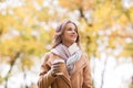 Happy young woman drinking coffee in autumn park Royalty Free Stock Photo